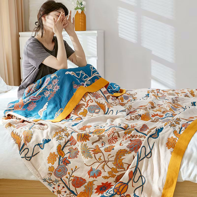 Woman Waking Up And Sitting In Bed With Regal Floral Brinley 1 Reversible Cotton Coverlet In Beige White Orange Yellow And Blue Colors Fall Pattern And Autumn Decor